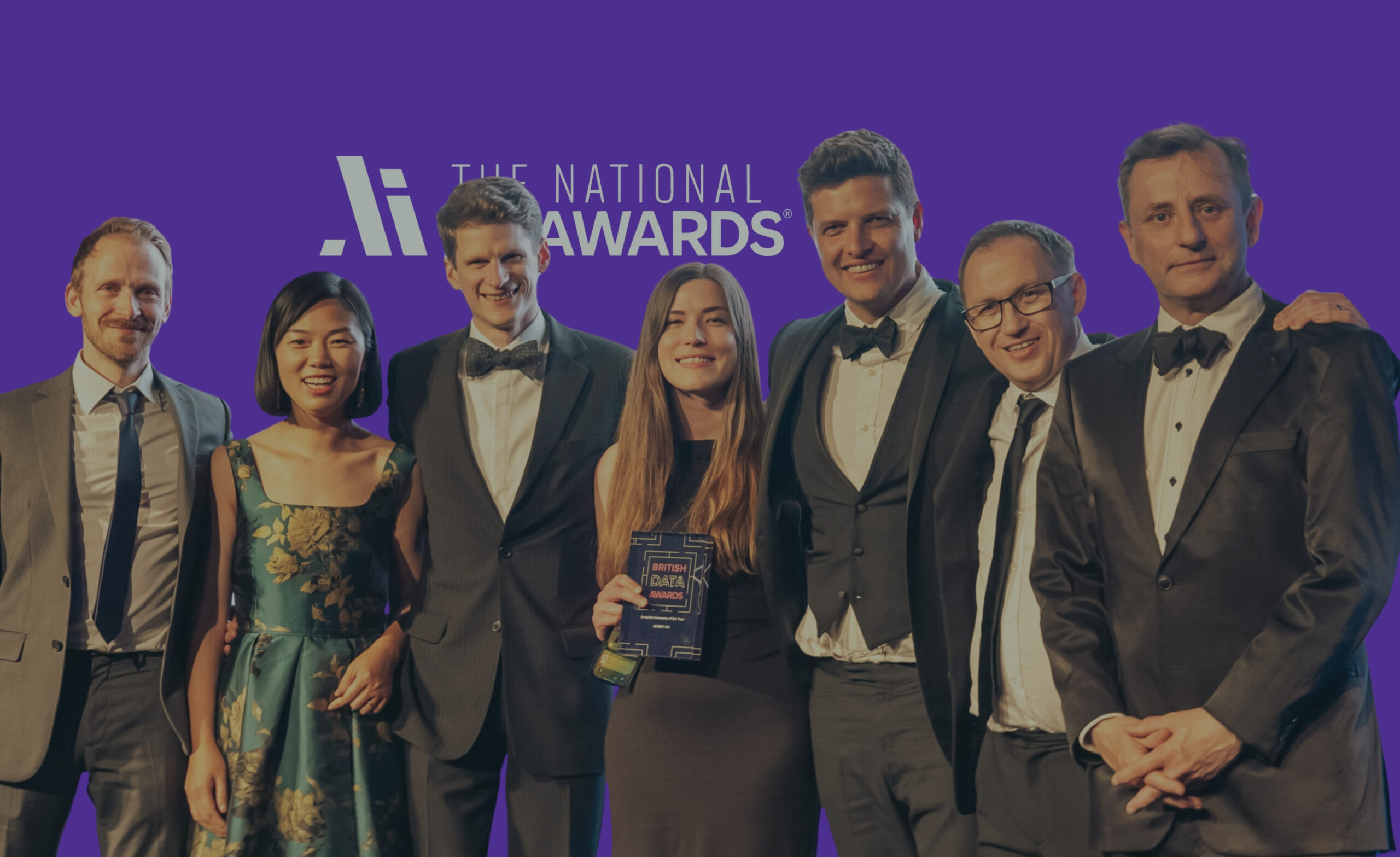 Group of AI innovators and industry leaders celebrating at The National AI Awards, set against a vibrant purple backdrop showcasing the official logo. Acknowledging excellence in artificial intelligence, data innovation, and ethical AI in the UK.